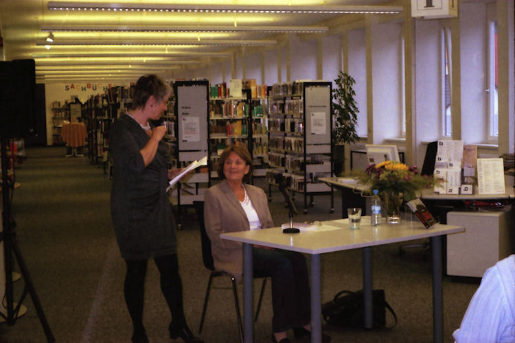 Die Leiterin der Bibliothek, Frau Baumgartner, begrüßt das Publikum und die Autorin Sigrid Ramge im vollbesetzten Veranstaltungsraum.